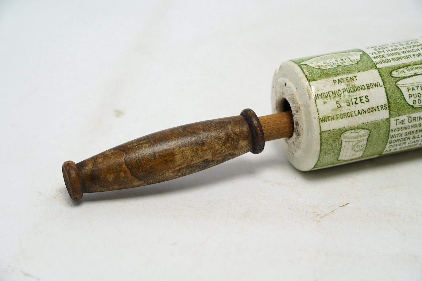 An early 20th century Grimwades green printed earthenware promotional rolling pin, 47cm wide. Condition - poor to fair